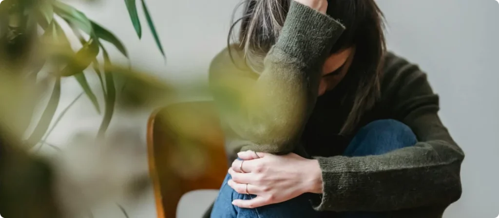 Person som sitter med hodet bøyd og armene foldet, som viser intens angst eller panikk